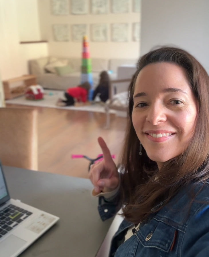 Tati Rosales sonriendo frente al computador mientras su hija juega sola al fondo
